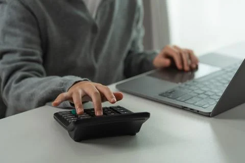Person working from home using calculator and laptop on white desk for fina.. 스톡 사진