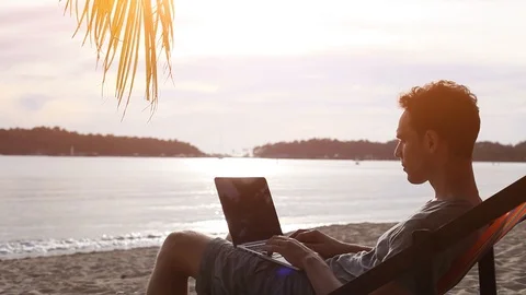Person working on laptop computer at sunset beach Stock Footage 108656517