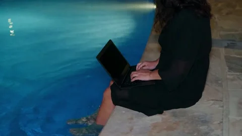 Person working on laptop poolside at tropical resort Stock Footage 344995577