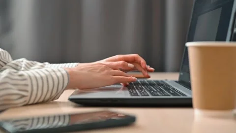 A person is working on a laptop while typing on a keyboard in a home office Stock Footage 339006055