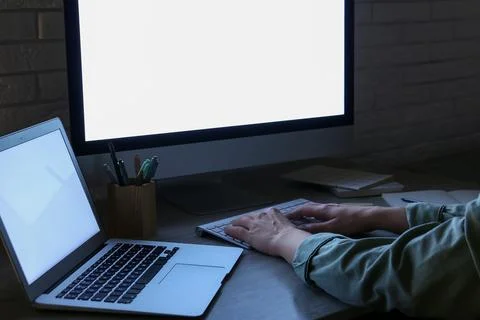 Person working late at night on computer and laptop with bright screens in a  Stock Photos