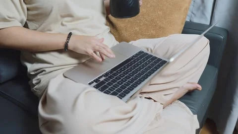 Person working remotely on laptop from comfortable couch, typing on keyboard Video stock 334461095