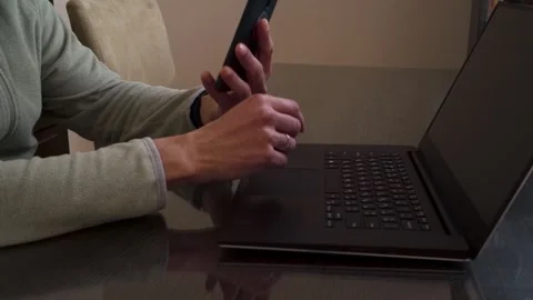 Person Working Remotely on Laptop, Multitasking with Smartphone at Home Stock Footage 331952545