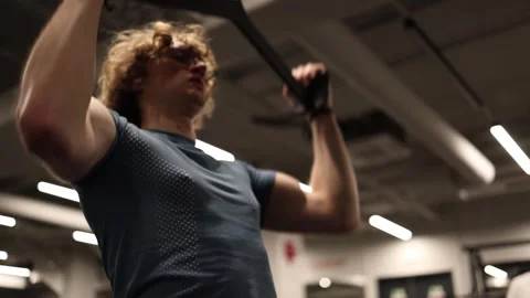 A person is working on their back muscles during a workout, lifting weights on a Stock Footage 301677267