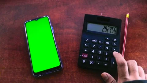 Person Working Using a Calculator And Watching a Smartphone With a Green Screen Video stock 170153494
