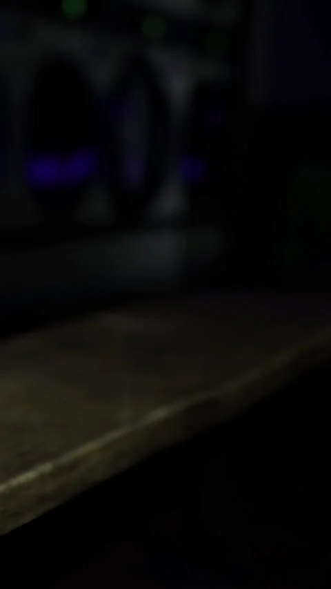 Person works on a computer in a dark room with colorful lights at night Видео 331680510