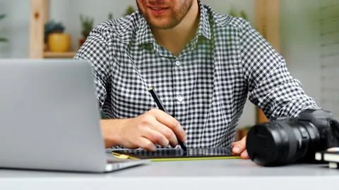 Person works on graphic design using tablet and laptop at home office in daytime Stock Photos