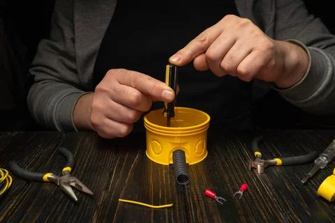 Person works on a yellow container while using tools in a dark workspace du.. Stock Photos