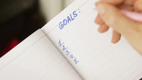 The person writes down a list of his goals in a notebook, plans. Stock Footage 252583802