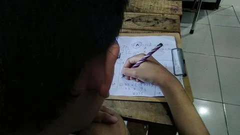 A person writes on a paper with math equations. Stock Photos