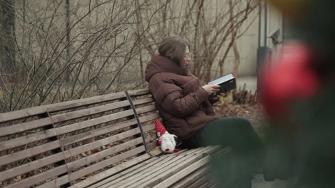 Person writes in park setting. Individual pens thoughts on peaceful park bench Stock Footage 345555428