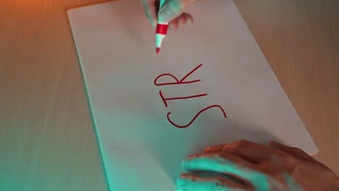A person writes words on paper, gradually completing the word stress. This Stockbeeldmateriaal 337558803