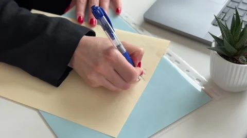 A person writing on an envelope at a modern workspace. Stock Footage 340526563