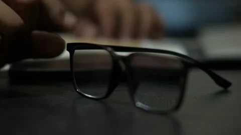 Person Writing in Notebook and Placing Eyeglasses on Desk Видео 345101949