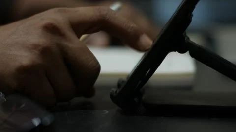 Person Writing in Notebook and Scrolling on Smartphone at Desk Stockbeeldmateriaal 345101487
