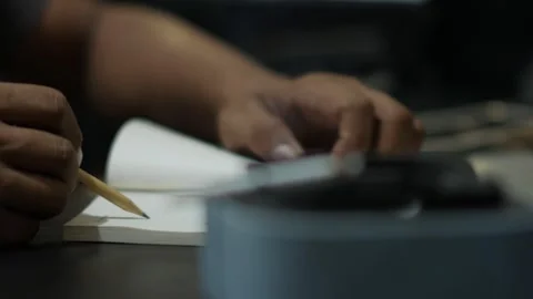 Person Writing in Notebook with Cigarette in Foreground Stockbeeldmateriaal 345101990
