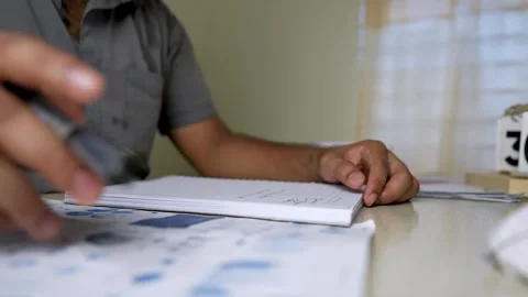 Person writing in a notebook at a desk with documents Stock Footage 315982889