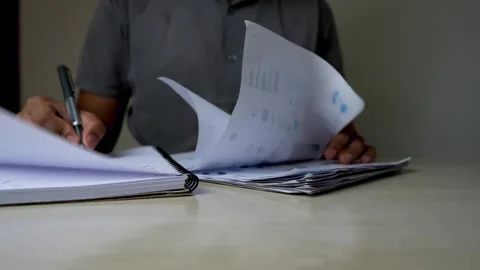 Person Writing in Notebook with Documents on Desk Stock Footage 315982734