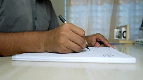 Person Writing in Notebook with Documents on Desk Stock Footage 315982757