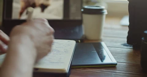 Person Writing in Notebook on Wooden Table with Laptop Vídeos de archivo 308379059