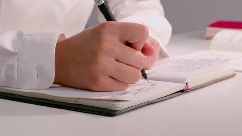 Person Writing Notes in Notebook on Desk, Close-up Shot Vidéo 334846298