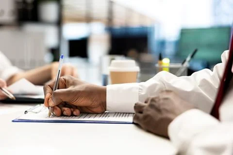 Person writing notes in a notebook at desk Stock Photos