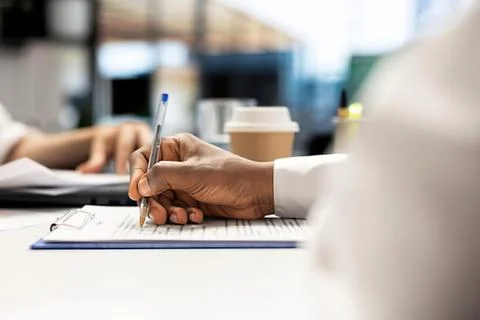 Person writing notes with pen on notepad 스톡 사진