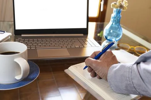 Person writing notes for remote work productivity Stock Photos