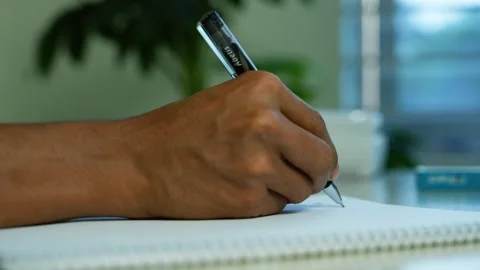 Person writing notes in a spiral notebook, Close-up of a person writing wit.. Stockbeeldmateriaal 346483854