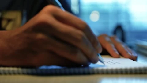 Person writing notes in a spiral notebook, Close-up of a person writing not.. Video stock 346483901