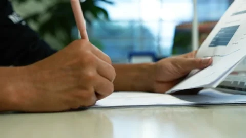 Person Writing Notes While Reviewing a Financial Report, Close-up of a pers.. 動画素材 345119983