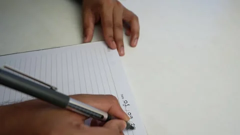 Person writing numbers in a notebook with a pen on a white surface Stock Footage 320724079