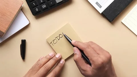 Person writing on sticky note to do list on table, making plan for work or .. Stock Footage 332407457