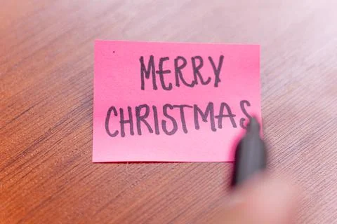 A person is writing on a sticky note on a table wood background. the person.. Stock Photos