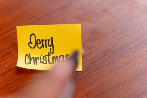 A person is writing on a sticky note on a table wood background. the person.. Foto stock