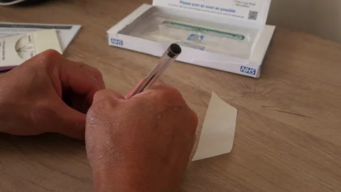 A person writing the test sample date on a bowel cancer test. Stock Footage 255781471