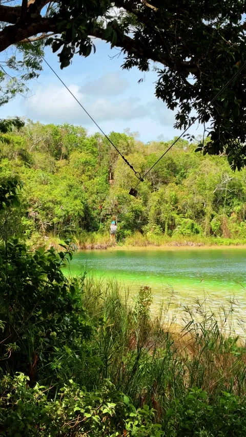 Person on zip line over green tropical lagoon Stock Footage 329072120