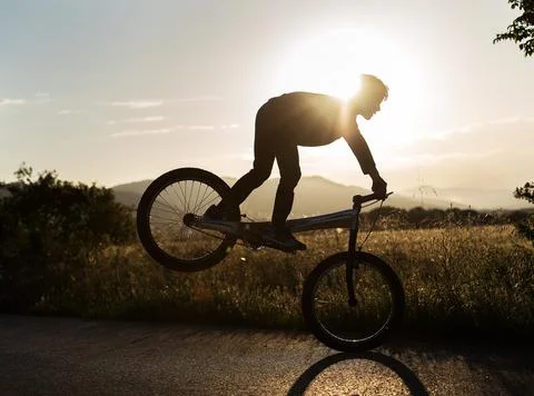 Persona saltando con la bicicleta a traves del sol Stock Photos