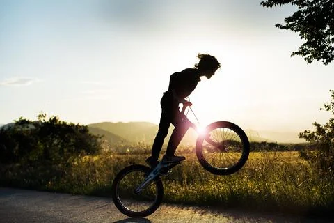 Persona saltando con la bicicleta delante del sol Stock Photos