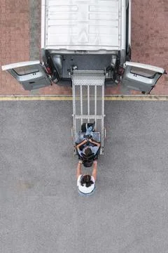 Personal assistant helping a man with disability leave a vehicle using a ramp Stock Photos