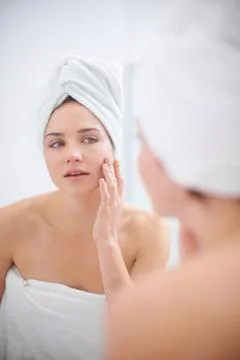 Personal beauty regime. A woman looking in her bathroom mirror with a towel on Stock Photos