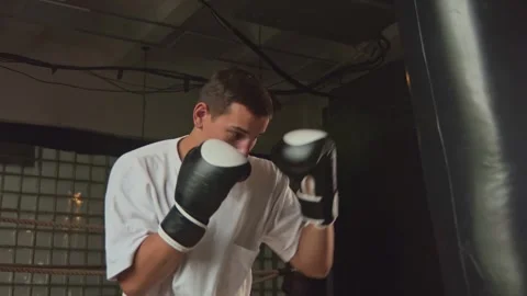Personal boxing trainer instructor beating big punching bag in modern gym Stock Footage 253508618