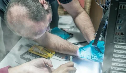 Personal computer technicians assembling new pc with the help of smartphone.. Stock Photos