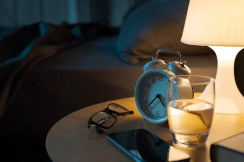Personal items on the bedside table in the bedroom Stock Photos