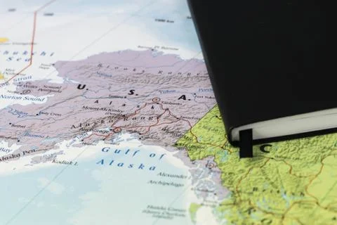 Personal notes of someone planning a trip to Alaska over a closeup map of Alaska Stock Photos