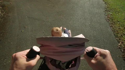 Personal perspective of a father pushing his daughter in a stroller Stock Footage 96188045