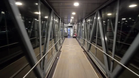 Personal perspective, last passenger walking through airport jet bridge at night Stock Footage 317552038