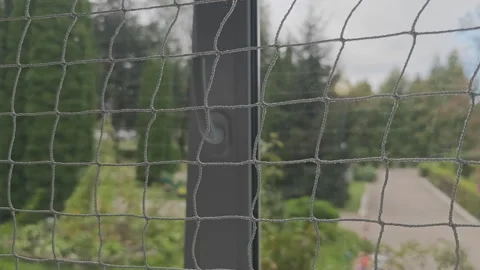 Personal perspective looking through a window with a protective safety net Stock Footage 344816170