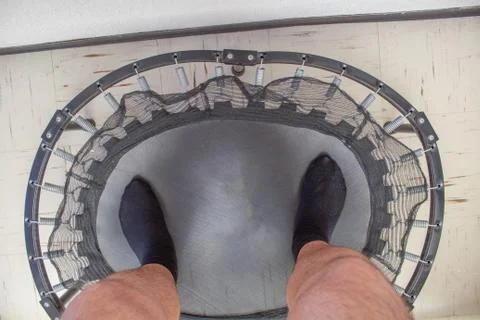 Personal perspective of man exercising on small trampoline 库存照片