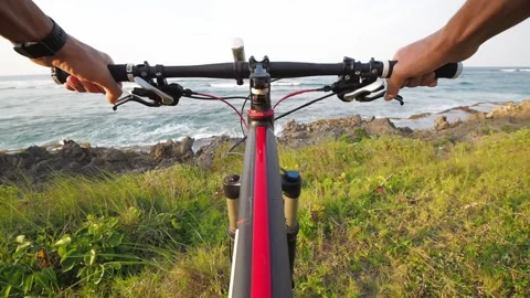Personal perspective. Mountain biker stands at ocean shore enjoying the view. Stock Footage 153882646